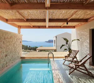 A residential interior featuring a swimming pool with a view of the sea and mountains, covered by a wooden pergola with a tha