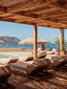 Sun-soaked wooden deck with lounge chairs, umbrellas, and a scenic coastal view.