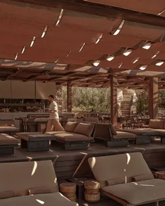 Indoor restaurant with rustic décor featuring wooden tables, stone walls, and natural light.