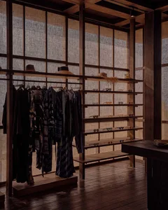 A beautifully designed retail shop interior featuring wooden walls, shelves, and clothing racks.