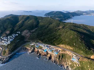 Aerial view of modern cliffside residences featuring concrete, glass, and stone materials.
