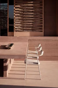 A minimalist outdoor seating area with wooden frames and fabric seats and backrests.