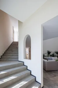 A concrete staircase leading to a hallway with a window.