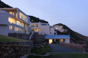 A modern residential building with illuminated windows and exterior lighting at dusk.