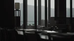 Empty modern restaurant with black glass and concrete bar, featuring sleek design and minimalist aesthetic.