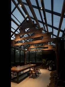 Industrial-style restaurant with wooden beams and glass ceiling.