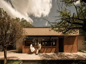 People enjoying drinks at a minimalist cafe with wooden features and outdoor seating.