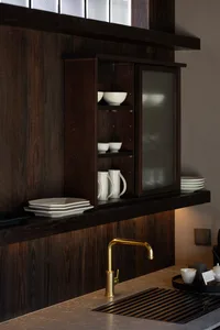 A modern minimalist kitchen with a wooden cabinet and white dishes.