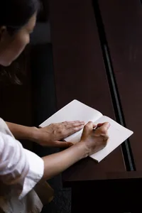 Person writing in a minimalist workspace using paper.