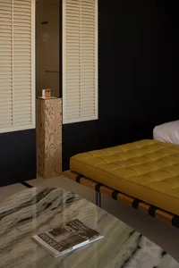 Modern bedroom with a yellow tufted leather couch and wooden accents.