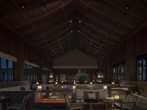 寬敞的現代酒店大廳，擁有高挑天花板、木樑、石桌與金屬椅。
