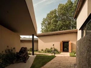 A modern house with a courtyard featuring concrete walls and a wooden door.