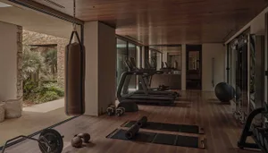 A modern indoor gym with a wooden floor and various workout equipment.