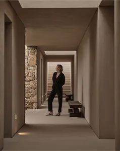 A person standing in a modern interior hallway with concrete walls and stone accents.