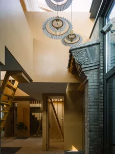 Modern entrance hall with wooden stairs, concrete walls, and wooden lantern chandeliers.