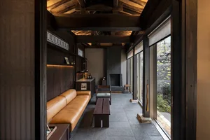 Modern living room with wooden beams, brown leather seating, and stone fireplace.