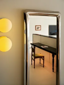 A minimalist home office featuring a sleek black desk and metallic mirror.