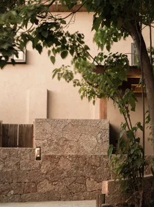 Modern residential exterior featuring a stone-clad wall and surrounding greenery.