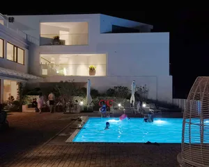 People enjoying a pool in a modern residential setting at night with illuminated windows.