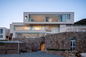 Modern house with white exterior, glass windows, and stone walls