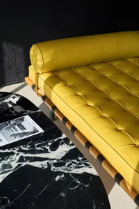 Modern furniture with yellow leather upholstery, featuring tufted design and wooden accents on a marble floor.
