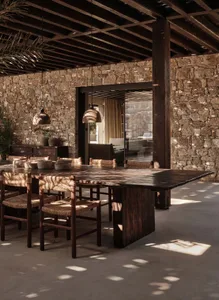 A rustic dining room with wooden furniture, stone walls, and a high ceiling with exposed beams.