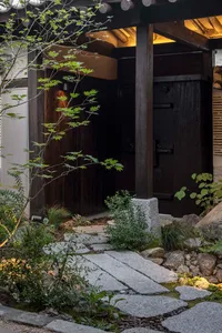 Stone pathway leading to wooden entrance with greenery