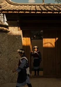 A traditional building corridor with wooden walls and stone walls, featuring a woman wearing traditional attire standing in a