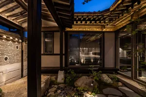 A traditional Korean house with wooden structures and stone pathways at night.