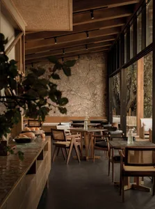 A wooden restaurant interior with stone accents and large windows.