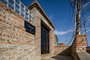 A brick building facade with a sign and a door.