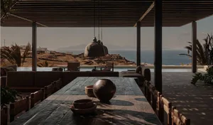 Minimalist outdoor living space with concrete and wooden materials, featuring a dining area, seating, and a pool with a view 