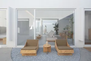 A minimalist living space featuring wooden furniture and glass walls.