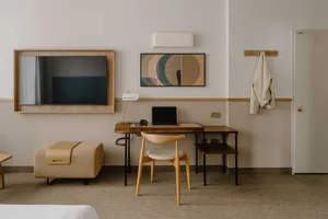 Modern, minimalist residential interior with wooden desk, digital tablet, and abstract art on the wall.