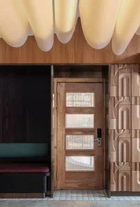 Modern wooden restaurant entrance with glass panels and bench seating.