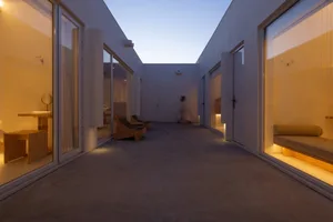 A modern residential interior with a concrete floor, glass walls, and natural light.