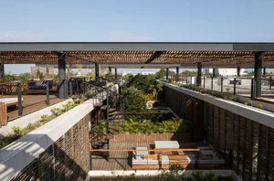 A modern indoor garden featuring wooden railings, concrete flooring, and metal stairs with greenery surrounding the area.
