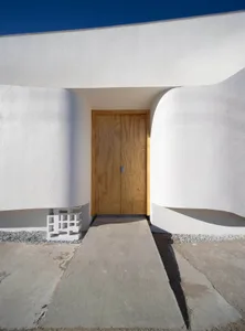A minimalist home entrance featuring a white plaster wall and a wooden door.