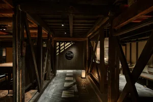 An industrial-style restaurant interior with a dark, wooden hallway leading to a seating area.