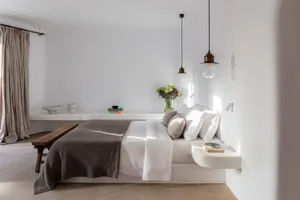 Modern minimalist bedroom featuring a concrete floating bed, white bedding, and minimalist decor.