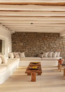 A minimalist living room featuring a natural stone wall and white furniture with accent pillows.