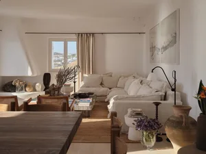 Minimalist living room with neutral tones, featuring a cozy sofa, wooden coffee table, and artistic wall decor.