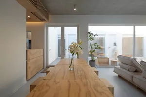 A minimalist living room with wooden furniture and a vase of flowers on the table.
