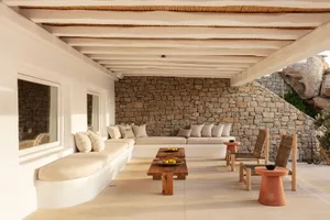 A minimalist residential patio featuring stone walls and comfortable seating areas.