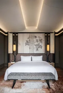 A modern bedroom featuring a textured wooden bed frame and headboard, with minimalist bedding and a bench at the foot of the 