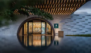 A modern hotel doorway framed by glass walls and a concrete ceiling.