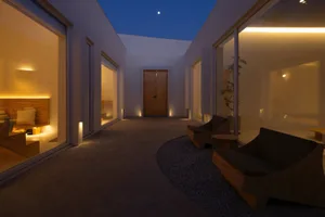A modern interior space featuring minimalistic furniture, concrete flooring, and warm lighting.