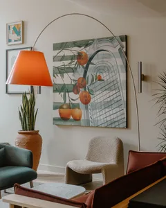 A modern living room with a potted plant, a retro floor lamp, and a retro sofa.
