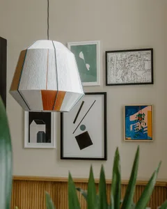 A modern living room featuring a geometric textile lamp hanging from the ceiling.