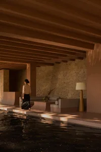 Modern lobby with concrete and stone walls, minimal furniture, and natural light.
